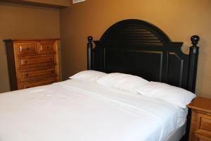 un letto con lenzuola bianche, una testiera nera e una cassettiera di 3 Bedroom condo at Wild Eagle Lodge a Eagle River Altre 31 foto
