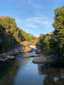 a river with rocks and trees on the side at Chalé Canarinho in Colinas Do Sul