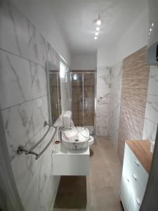 a white bathroom with a sink and a shower at Apartmani Vrzić in Baška