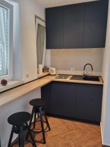 una cocina con armarios negros y 2 taburetes en Adriatic View Studio Apartments, en Dubrovnik 21 fotos más