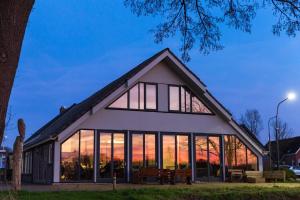 a house with large windows and a sunset at Vallei - appartement de Es in Rolde
