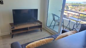 Departamento Mirador al Volcan في فيلاريكا: غرفة معيشة مع تلفزيون بشاشة مسطحة وطاولة مع كراسي