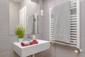 a white bathroom with a sink and a mirror at Bella Apartments No2 in Hajdúszoboszló