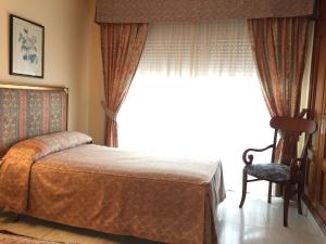 a bedroom with a bed and a window with a chair at Hotel Restaurante Derby in Carballino