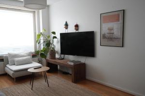 a living room with a flat screen tv and a chair at A two-bedroom with river view in Kajaani