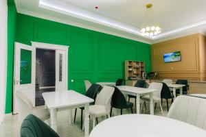 a restaurant with green walls and white tables and chairs at Resident Hotel in Tashkent