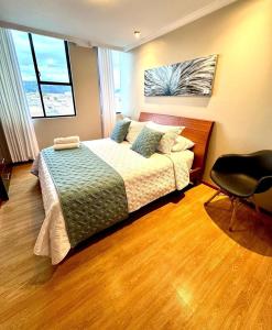 une chambre avec un lit et une chaise dedans dans l'établissement Acogedor Apartamento en Cuenca, à Cuenca