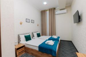 a bedroom with a bed with blue sheets and a tv at Resident Hotel in Tashkent