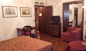 um quarto de hotel com uma cama e uma cadeira e uma televisão em Hotel Piccola Fenice em Veneza