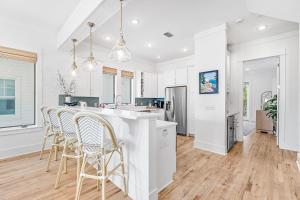 a kitchen with white walls and a bar with chairs at Sand On Tap in Inlet Beach