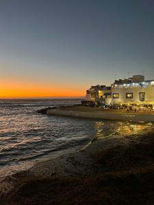 a beach with a building and the ocean at sunset at Casalegre in El Cotillo