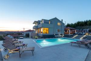 uma casa com piscina em frente a uma casa em VIlla Laetitia em Žrnovnica