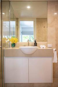 a bathroom with a white sink and a mirror at Villa 437 Coral Shore Villa in Port Douglas