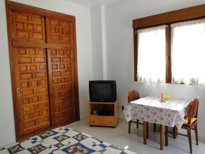Habitación con mesa, TV y puerta. en Los Geraneos en Águilas