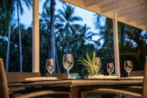 a wooden table with four wine glasses on it at Villa 437 Coral Shore Villa in Port Douglas