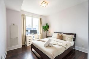 a white bedroom with a large bed and a desk at Luxury Condo with Pool, CN Tower View, Gym, Workspace in Toronto +35 photos