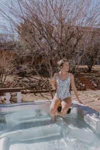a woman sitting on the side of a swimming pool at Stylish Home with Hot Tub, Ping Pong, Pickleball, Electric Scooters and Pet Friendly in Big Bear City