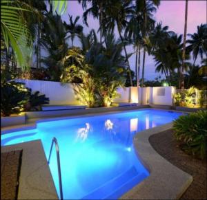 ポートダグラスにあるBeachLuxe Sunseeker, Sublime Tropical Apartmentのヤシの木が茂る裏庭のスイミングプール
