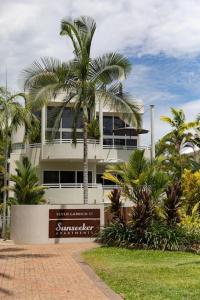 ポートダグラスにあるBeachLuxe Sunseeker, Sublime Tropical Apartmentの前にヤシの木がある建物