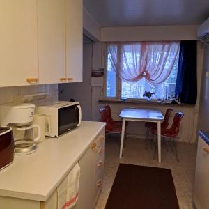 a small kitchen with a table and a microwave at Karhunkierros Apartment in Hautajärvi
