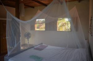 a bedroom with a bed with a mosquito net at Casa del Mar - El Zanate in Las Peñitas