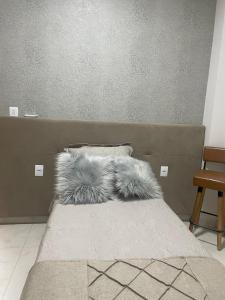 a bed with furry pillows on top of it at Studio Home in Patrocínio