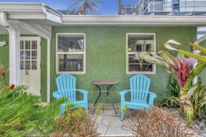 two blue chairs and a table outside a green house at Stones Throw Beachside Bungalow #2 AT THE BEACH in Clearwater Beach
