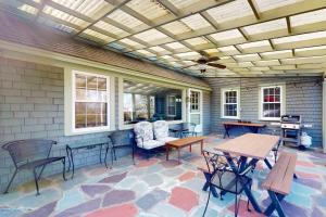 eine Terrasse mit Tischen und Stühlen und einer Decke in der Unterkunft Cape Landing Cottage in Brewster
