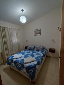 a bedroom with a bed with a blue and white comforter at Cabañas Margus in La Granja