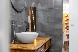 a bathroom with a white bowl sink on a wooden counter at Oenosuite - Charme & Vin en hyper-centre in Dijon +16 photos