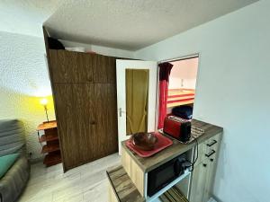 a small kitchen with a microwave on a counter at Résidence Les Quatres Saisons - Appartement à l'entrée du Village de Corrençon, départ des navettes gratuites au pied de la résidence MAE-4004 in Corrençon-en-Vercors +1 photo