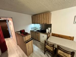 a small kitchen with a table and a bed in a room at Résidence Les Quatres Saisons - Appartement à l'entrée du Village de Corrençon, départ des navettes gratuites au pied de la résidence MAE-4004 in Corrençon-en-Vercors