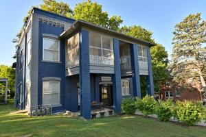 a blue house with a balcony on a lawn at Sr Pilot Earhart Hangar Suite, 2 br K &Q, 1 Ba in Atchison