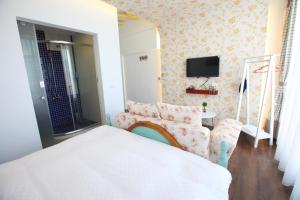 a bedroom with a bed and a couch and a tv at Qing Noise Villas in Hualien City