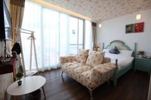 a bedroom with a couch and a bed with windows at Qing Noise Villas in Hualien City