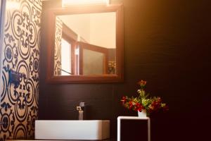 ein Badezimmer mit Waschbecken, Spiegel und einer Vase mit Blumen in der Unterkunft Kesaviyam Unique Ocean View Luxury Suites vicinity Kovalam Light house in Kovalam + 59 Fotos