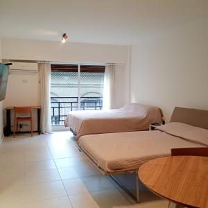 Una habitación con dos camas y una mesa y una ventana. en Excelente departamento céntrico cerca de todo, en Buenos Aires