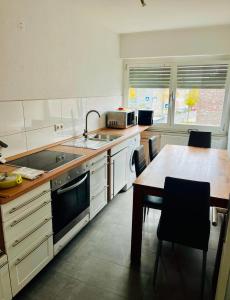 cocina con armarios blancos, mesa y fregadero en PF Apartments S1, en Eschweiler