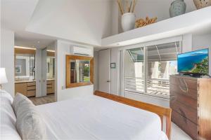 a white bedroom with a bed and a tv at The Palms at Wailea 702 in Wailea +36 photos