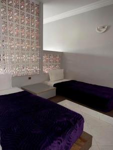 a room with two beds with purple sheets and a wall at Hôtel Résidence Louban in Agadir
