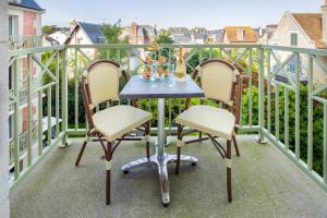 a table on a balcony with two chairs and a bottle of champagne at La Closerie SPA & Résidence Hôtel in Deauville