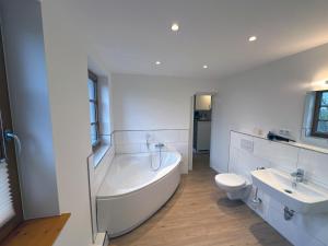a large white bathroom with a tub and a toilet at Lassen Hof Ferienwohnung 01 Bienenstock in Brodersby