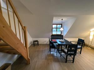 a dining room with a table and chairs and a staircase at Lassen Hof Ferienwohnung 01 Bienenstock in Brodersby