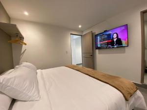 a bedroom with a bed with a flat screen tv on the wall at 96K Premium Suite - Habitaciones a minutos del Aeropuerto en Bogotá in Bogotá