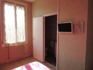 a bedroom with a toilet and a television on a wall at Hotel Le Colbert epernay in Épernay