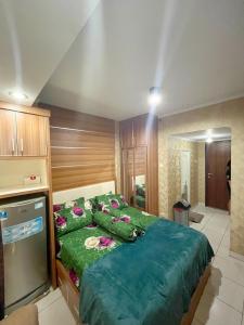 a bedroom with a large bed with green sheets and flowers at Disewakan Studio Fully Furnished Metropolitan Park Apartement - Bekasi in Telukpucung
