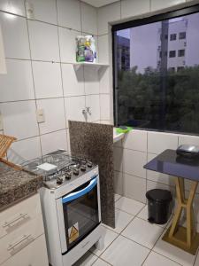 a kitchen with a stove and a table and a window at Apartamento aconchegante in Teresina