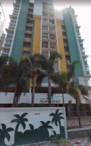 a tall building with palm trees in front of it at Luxe Oasis Palm Opposite LULU Mall Thiruvananthapuram in Trivandrum