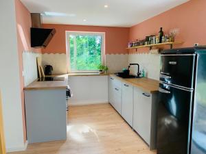 Una cocina con gabinetes blancos y un refrigerador negro. en Auszeit am Schwielowsee - Exklusiver Bungalow mit Seeblick, en Schwielowsee
