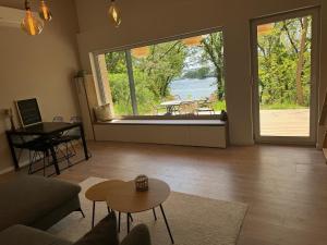sala de estar con ventana grande y mesa en Auszeit am Schwielowsee - Exklusiver Bungalow mit Seeblick, en Schwielowsee 16 fotos más